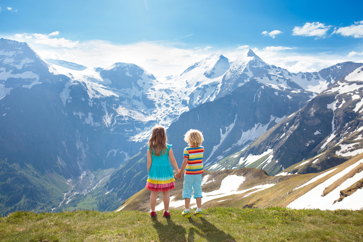 The image shows a little boy and girl looking at a beautiful mountainscape. The goal is to explain if high altitudes are safe for kids with asthma.