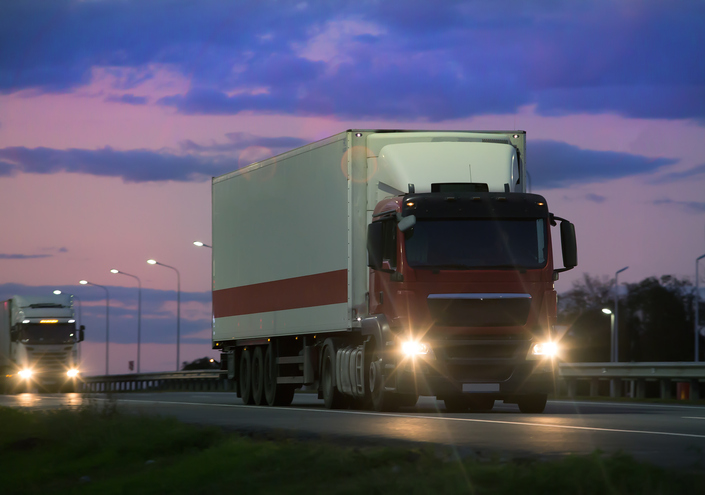 Image of semi trucks on the road at dawn as the featured image for "Sleep Hygiene Tips for Shift Workers"